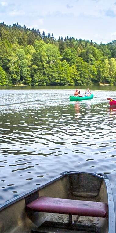 Menschen paddeln in Kanus durchs Wasser.