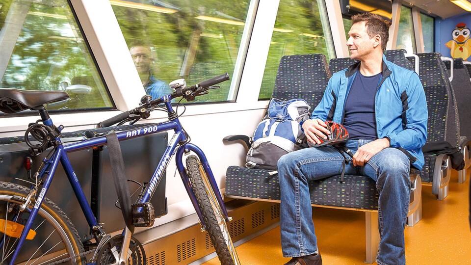 Mann sitzt mit seinem Fahrrad in der Bahn